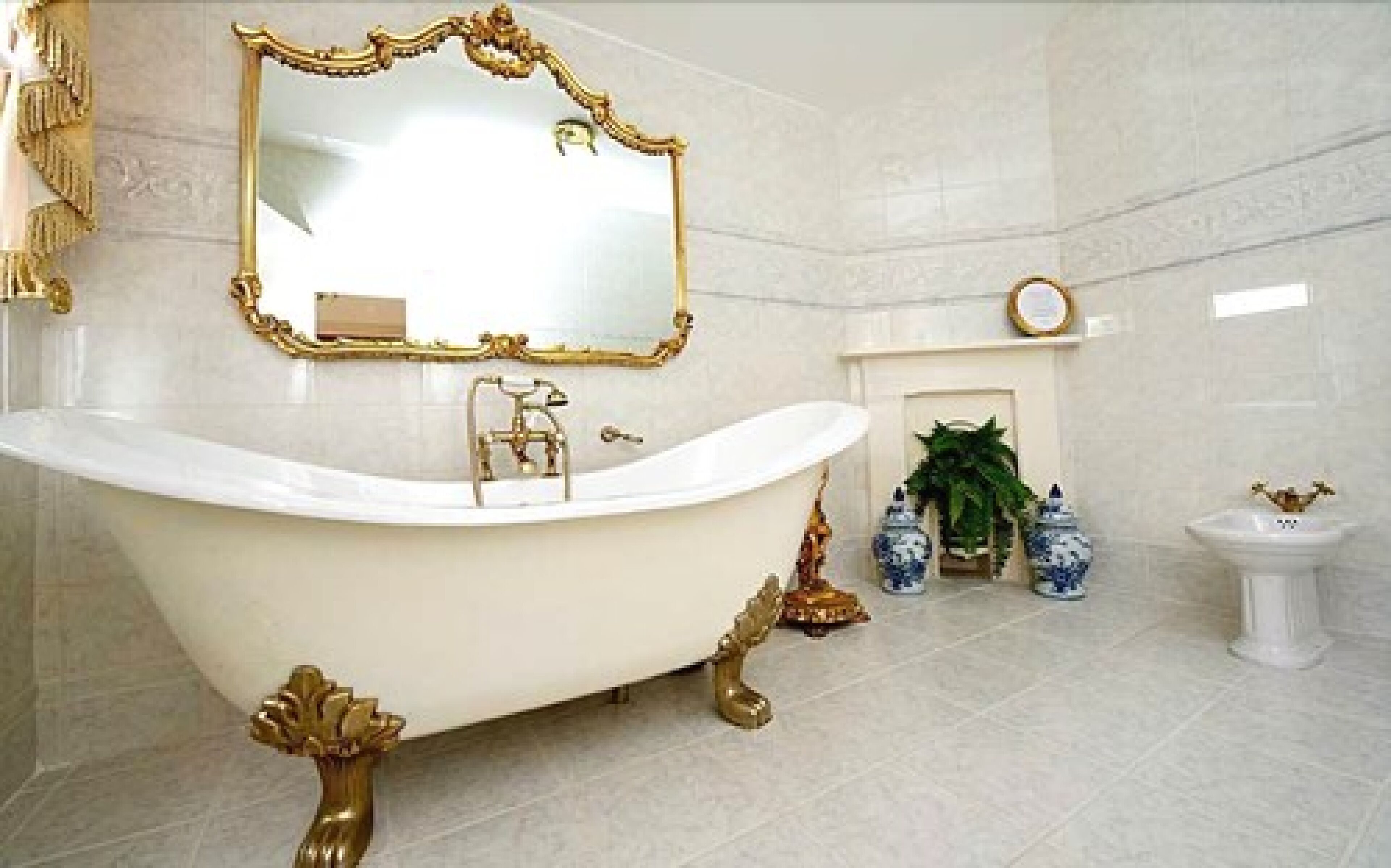 A luxurious bathroom with a freestanding bathtub, a large mirror with an ornate frame, a small fireplace, and decorative vases.