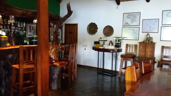 A rustic bar area with wooden furniture, a green wall, and various bar items.