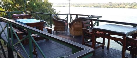 A wooden deck with outdoor furniture, including a table and chairs, overlooking a body of water.