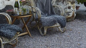 An outdoor seating area with wicker chairs and a table, a bottle of wine, and a vase with flowers. - Wanås Restaurant Hotel (Knislinge)