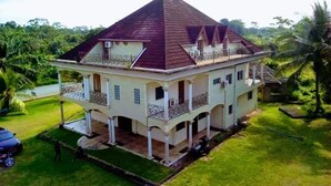 A two-story house with a steeply pitched roof, a balcony on the upper floor, and a well-maintained lawn.