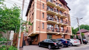 A multi-story building with balconies, a staircase leading to the entrance, and parked cars in front. - Catherine Hotel (Chisinau)