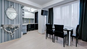 A modern hotel room with a dining area, a large mirror, and a TV. - Catherine Hotel (Chisinau)