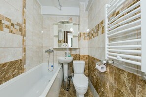 Et badeværelse med badekar, vask, toilet og et spejl.