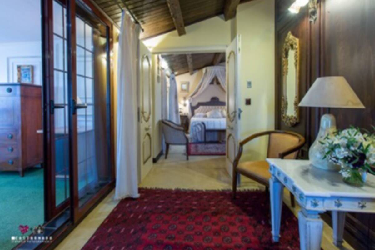 Una habitación con una cama, una silla, una mesa con lámpara y un espejo en la pared.