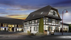 En moderne bygning med en traditionel bindingsværksfacade, store vinduer og et godt oplyst indgangsparti.