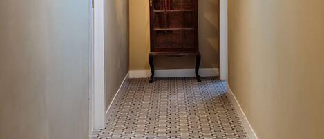 A narrow hallway with patterned flooring, a wooden bookcase, and a skylight.