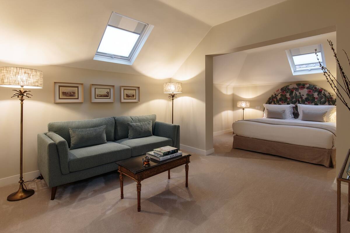 A bedroom with a bed, a sofa, a coffee table, and a skylight.