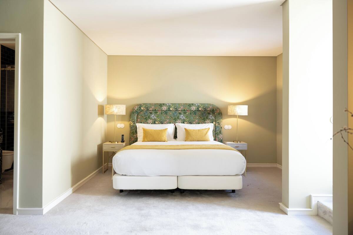 A bedroom with a large bed, two bedside tables, and a headboard with floral patterns.