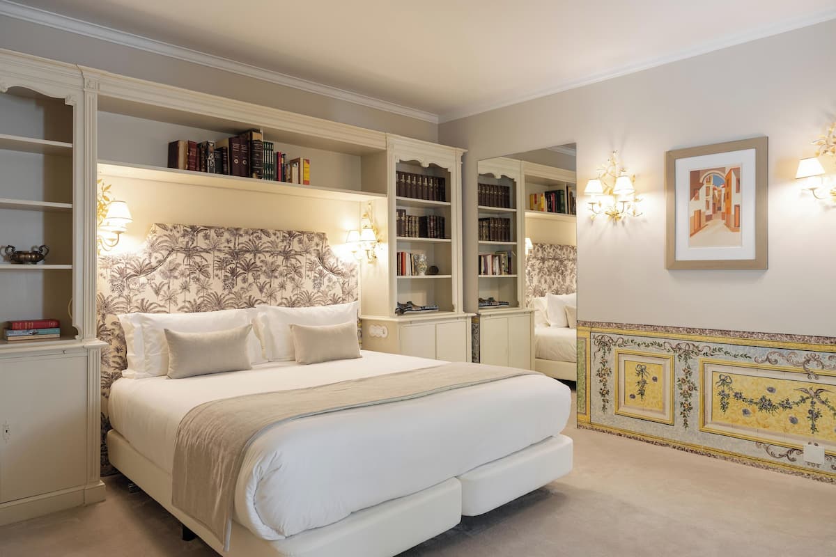 A bedroom with a large bed, built-in bookshelves, and a decorative mirror.