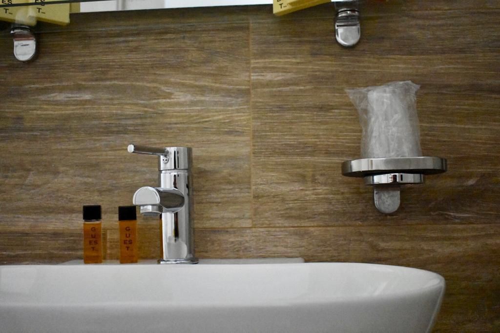 Un baño con un lavabo blanco, grifo cromado y dispensador de toallas montado en la pared.