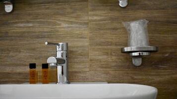 Un baño con un lavabo blanco, grifo cromado y dispensador de toallas montado en la pared.