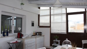 Una cocina con encimera blanca, un lavamanos, una estufa y una zona de comedor con mesa y sillas.
