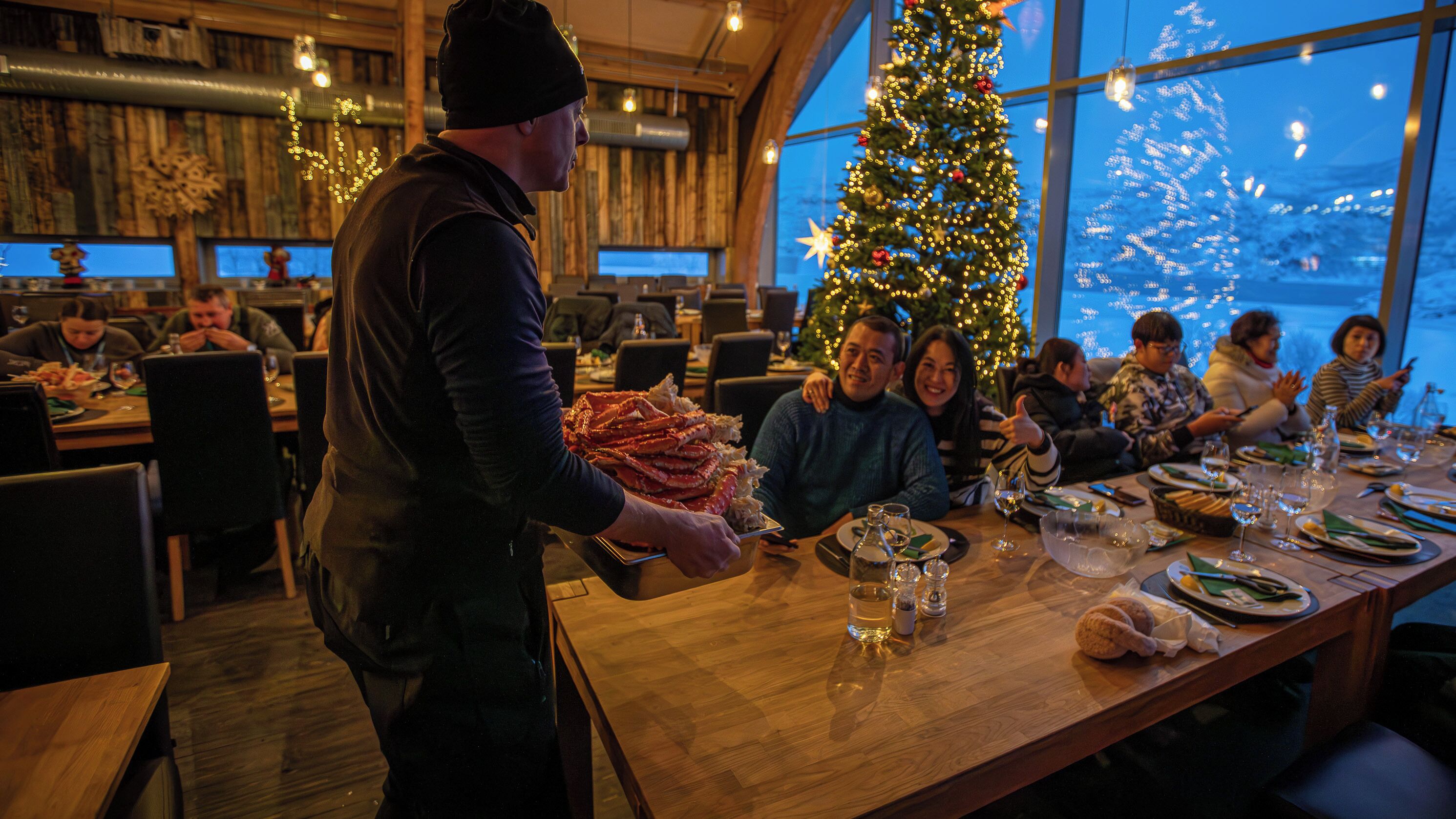 Ein Restaurant mit Holzvertäfelung, einem Weihnachtsbaum und Gästen.