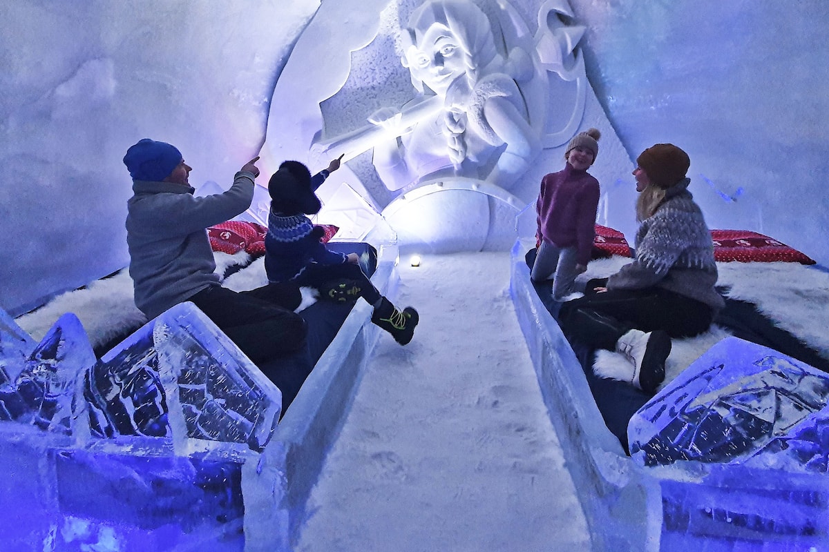 An ice sculpture with a face, surrounded by people.