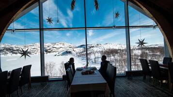Un comedor con un amplio ventanal de arco que da a un paisaje nevado.