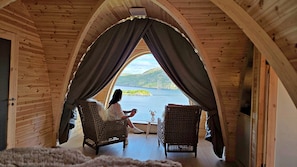 Una habitación acogedora con vistas a un lago, que incluye dos sillas de mimbre y una mesa.