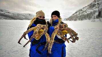 Two individuals holding large crabs in a snowy outdoor setting.