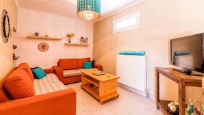 A cozy living room with a sofa set, a wooden coffee table, a TV, and decorative items on shelves. - Antonela Sunshine Apartment by CorfuEscapes (Corfu)