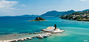 Eine Küstenstadt mit einer weißen Kirche auf einer kleinen Insel, klarem türkisblauem Wasser und einem Pier mit Booten.