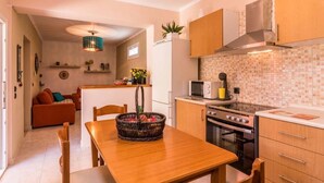 A compact kitchen with a dining area, a microwave, an oven, and a refrigerator. - Antonela Sunshine Apartment by CorfuEscapes (Corfu)