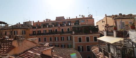 Un edificio de varios pisos con tejados de tejas color terracota, balcones y cielo despejado.