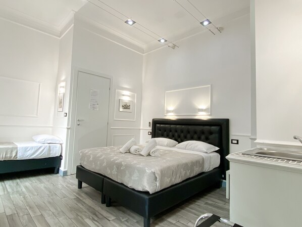 A hotel room with a large bed, a smaller bed, a vanity with a mirror, and a ceiling light fixture.