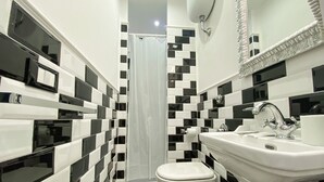 A bathroom with black and white checkered tiles, a white sink, a toilet, and a shower curtain. - Locanda Parlamento (Rome)
