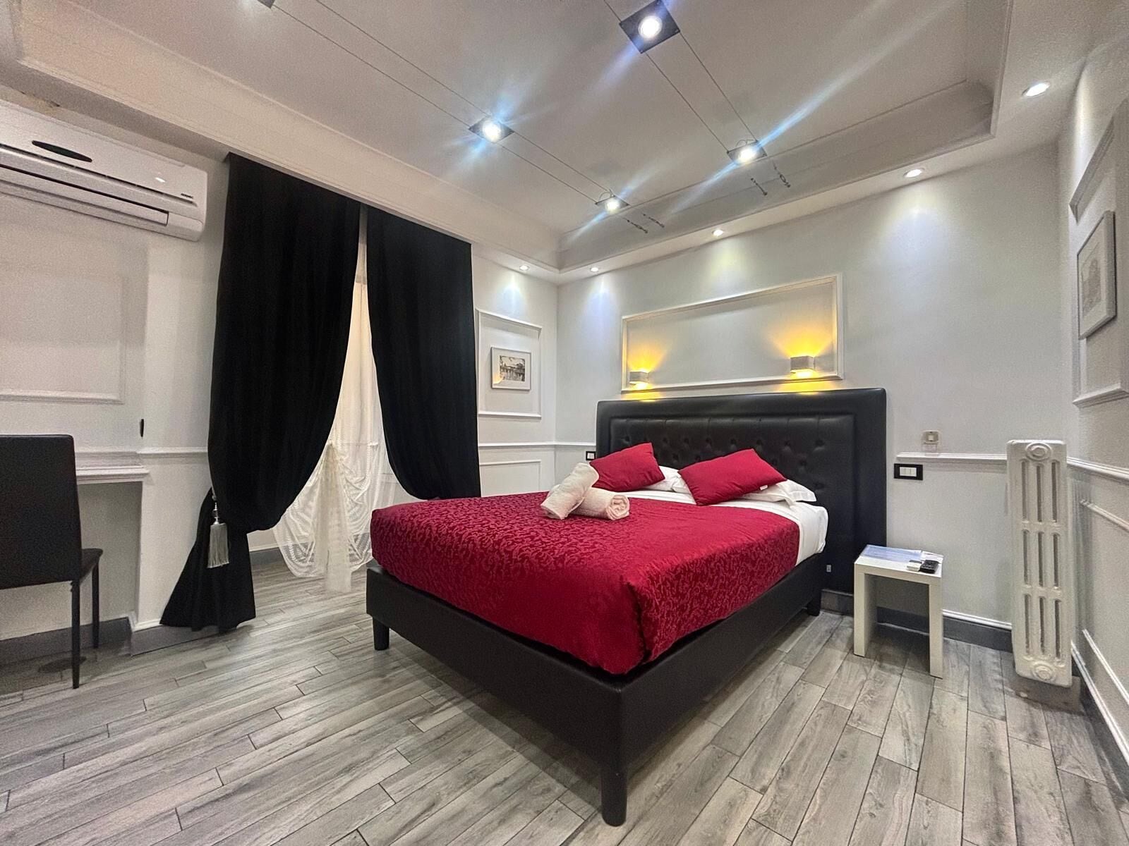 A modern bedroom with a large bed, a bedside table, a chair, and a radiator.