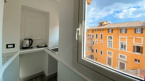 A small kitchen with a kettle, a sink, and a window overlooking a building with orange facades. - Locanda Parlamento (Rome)
