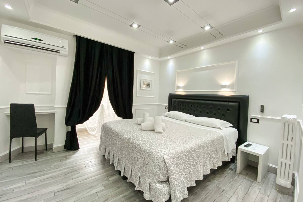 A modern bedroom with a large bed, a desk, and a chair.