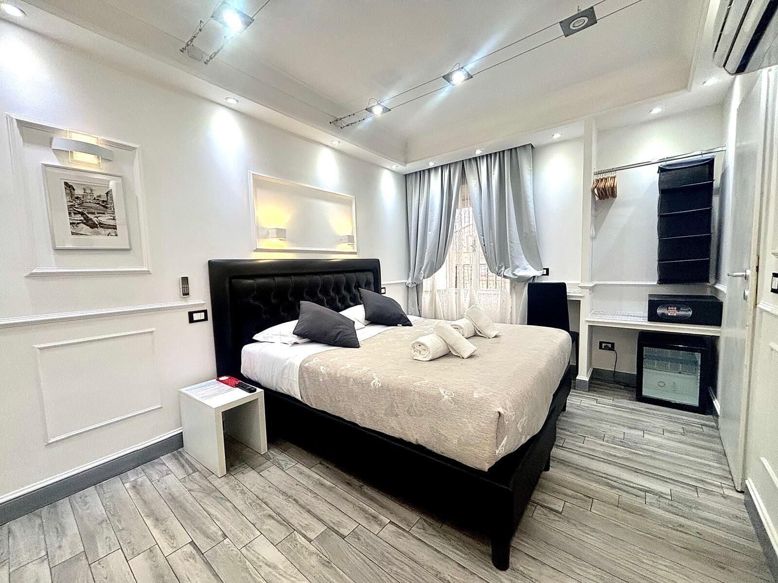 A modern bedroom with a large bed, bedside tables, a desk, and a wardrobe.