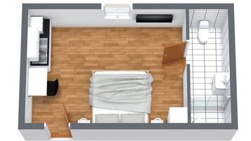 A modern hotel room with a bed, a desk, a chair, a small table, a sofa, a bathroom with a toilet and sink, and a window.