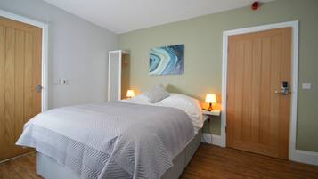 Une chambre à coucher avec un lit, deux lampes de chevet, une œuvre d’art murale et deux portes en bois.