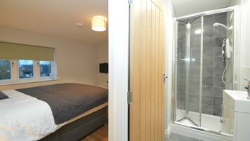 Un dormitorio con cama y un baño con ducha.