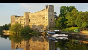 Un castillo histórico con un foso, un puente y una barca amarrada junto al agua.