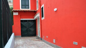 Een smalle steeg met een rood gebouw, een zwart hek en een betegelde vloer.