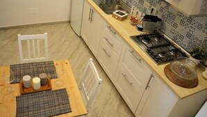 Een compacte keuken met witte kastjes, een houten aanrecht, een gasfornuis en een spoelbak.