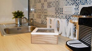 Een keuken met een spoelbak, een kamerplant, een koffieapparaat en een houten doos met de tekst 'HOME'.