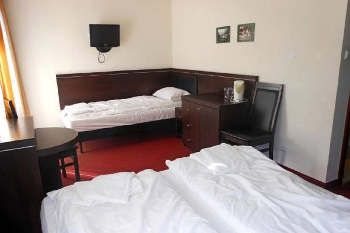 Habitación de hotel con dos camas, un escritorio, una silla y una mesita.