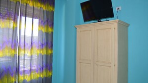 Ein Zimmer mit blauer Wand, einem Holzschrank und einem flachbildfernseher, der oben angebracht ist.