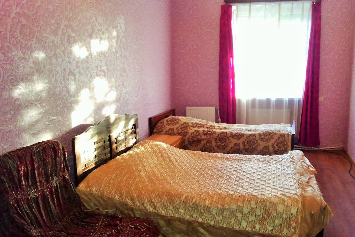 Une chambre avec deux lits, un radiateur et une fenêtre avec des rideaux.