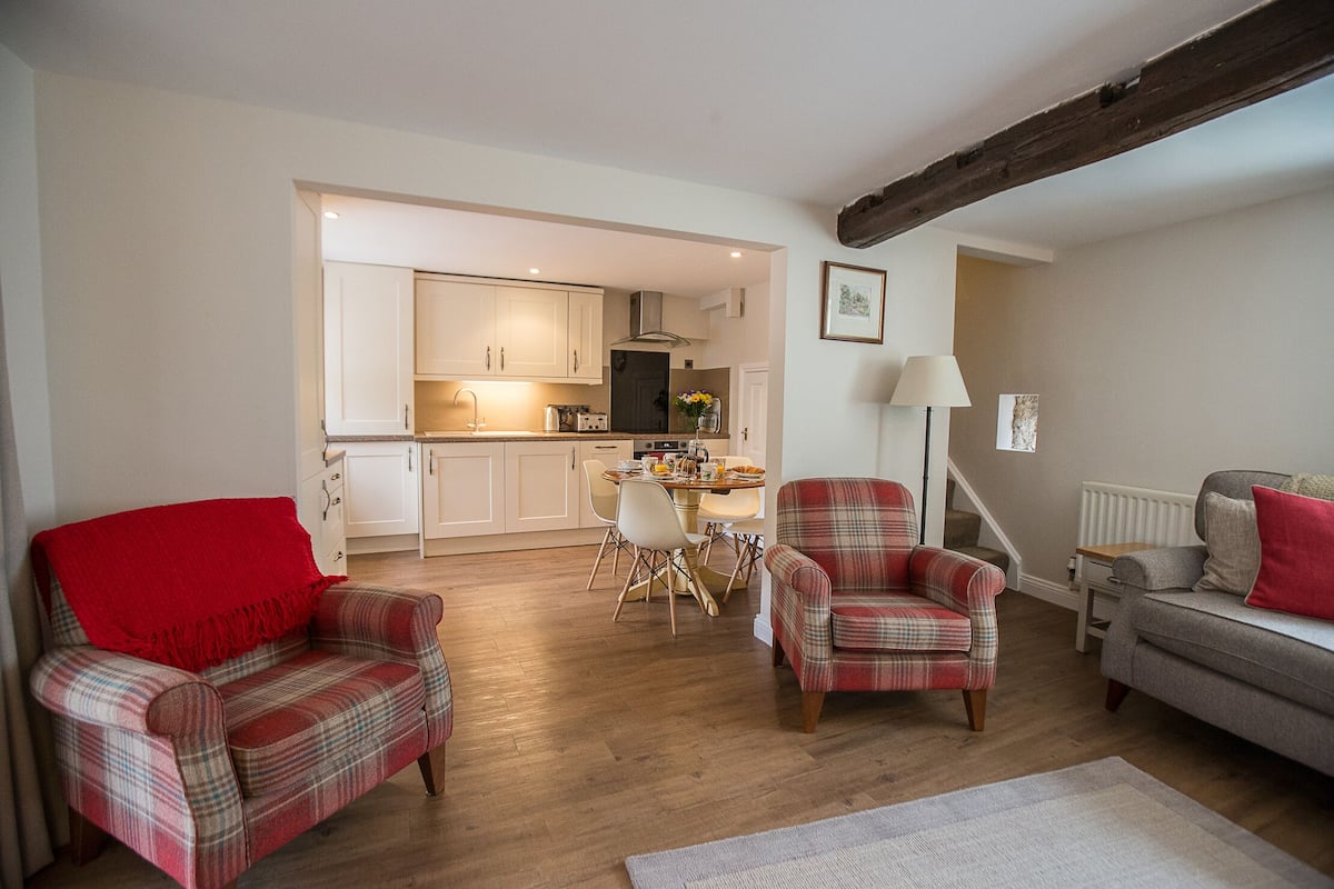A living room with two plaid armchairs, a sofa, and a dining area with a table and chairs.
