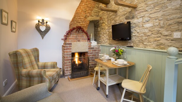 A cozy room with a fireplace, a television mounted on the wall, and a table set for dining.