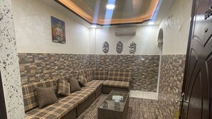 A modern living room with a sectional sofa, a coffee table, and decorative wall art. - Amaled Hotel (Amman)