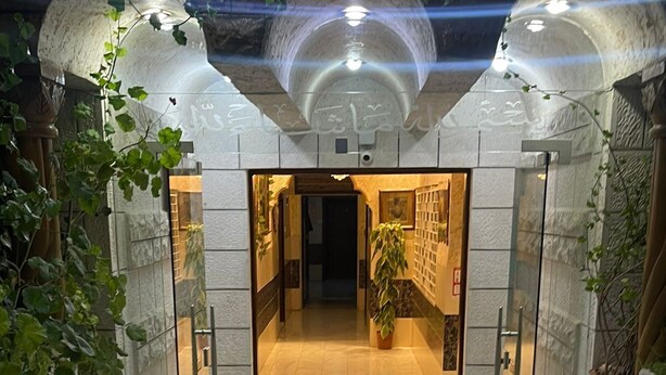 A hallway with a marble floor, glass doors, and potted plants. - Amaled Hotel (Amman)