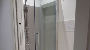 Un baño moderno con ducha acristalada, inodoro blanco y suelo de madera.