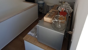 Una cocina compacta con un refrigerador blanco, una encimera de madera y un lavabo.