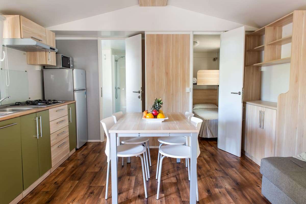 A compact kitchen with a dining area, a microwave, a refrigerator, and a wooden cabinet.