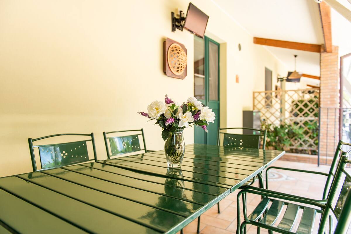 A dining table with chairs, a vase with flowers, and a wall-mounted decorative piece.